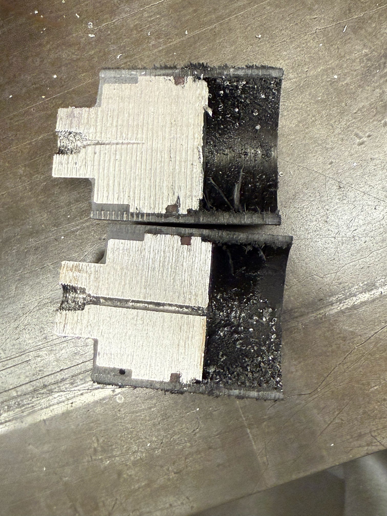 Sectioned composite and metal test hardware on a workbench.